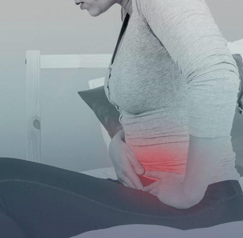Ao fundo da imagem, há uma mulher sentada com as mãos no intestino e um efeito vermelho no local representando a dor.
