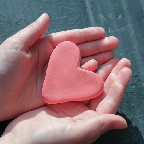 A imagem mostra uma mão segurando um coração feito de massa de modelar
