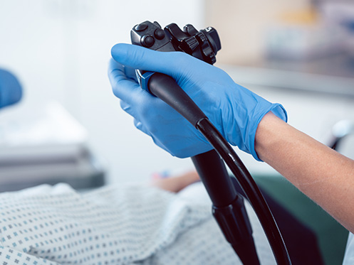 Imagem mostra um médico segurando um equipamento para fazer colonoscopia.