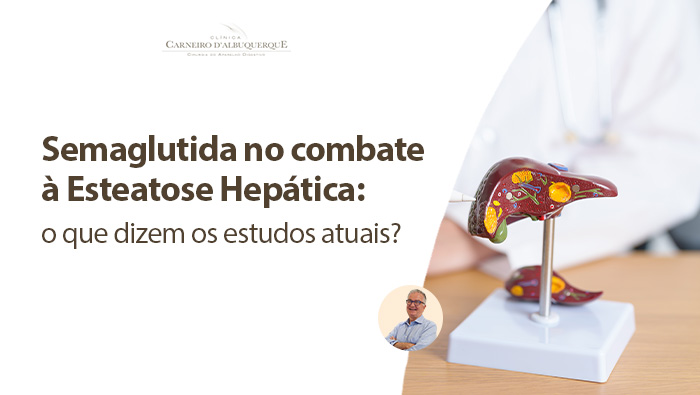 Médico apontando com uma caneta para um modelo anatômico de fígado sobre uma mesa, explicando a estrutura e possíveis condições hepáticas, com estetoscópio no pescoço.