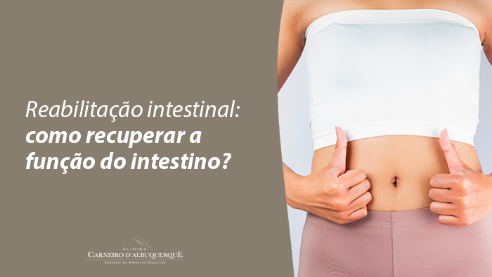 Mulher em roupa de ginástica mostra a região abdominal e faz sinal de positivo com as duas mãos, simbolizando saúde e recuperação intestinal.