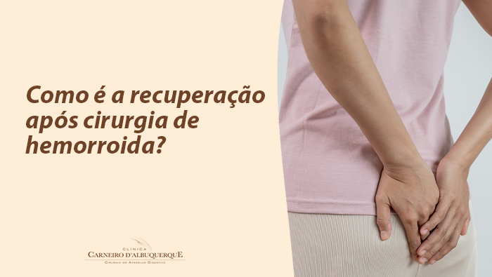 Pessoa com as mãos apoiadas na região glútea, indicando desconforto ou dor, vestindo camiseta rosa e calça clara, em fundo neutro.